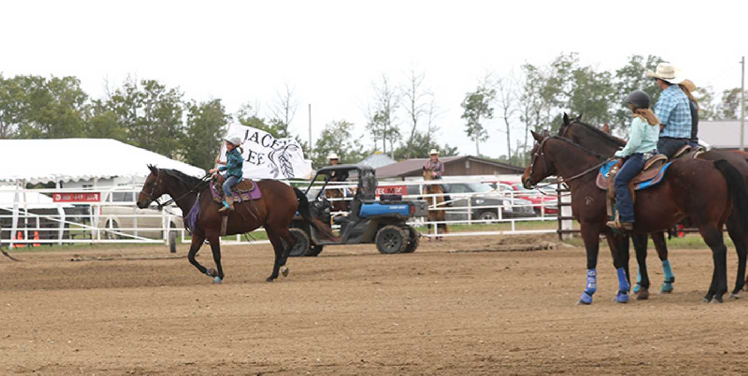 One of the kids participating in the 2023 Jacey Lee Memorial Barrel Racing event holding a flag in memory of Jacey Lee. Photo by: Sunnette Kamffer.